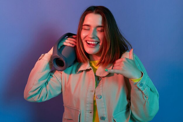 Retrato de una mujer fresca y feliz con una elegante chaqueta posando aislada en un fondo de luz de neón disfrutando de la música con la columna manteniendo los ojos cerrados expresando emociones positivas