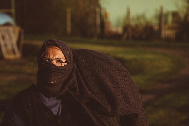 Retrato de una mujer con gafas y pañuelo en la cara al aire libre