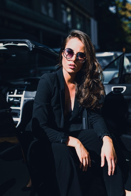Retrato de una mujer con gafas de sol mientras está sentada en la ciudad