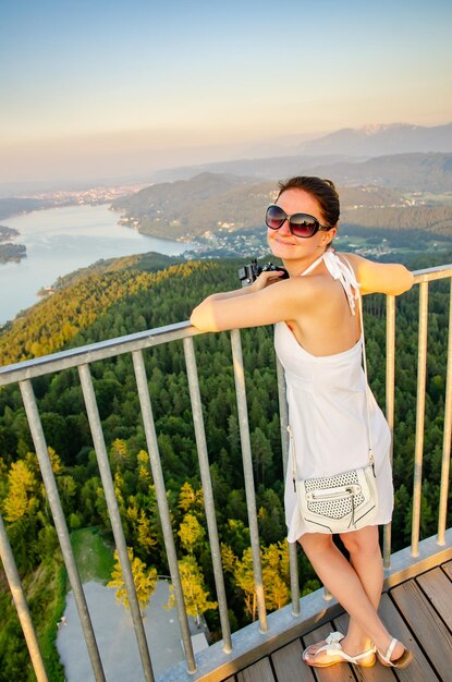 Foto retrato de una mujer con gafas de sol mientras está de pie en un punto de observación contra el paisaje