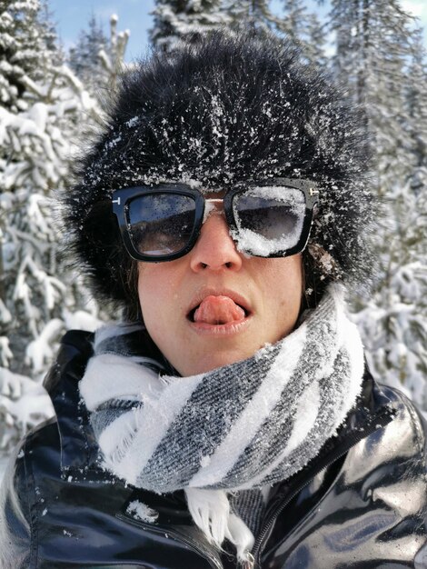 Foto retrato de una mujer con gafas de sol en la nieve