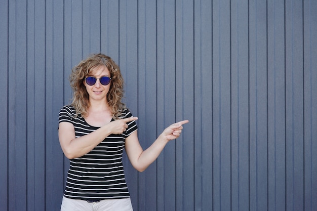 Retrato de mujer con gafas de sol en la pared de rayas azules en el fondo