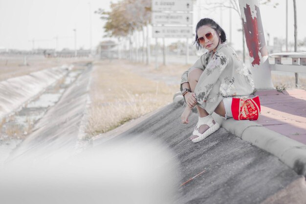 Foto retrato de una mujer con gafas de sol sentada al aire libre.