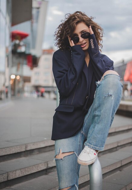 Retrato de una mujer con gafas de sol sentada en la barandilla