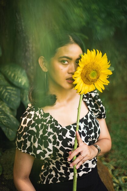 Retrato de una mujer con girasol de pie al aire libre