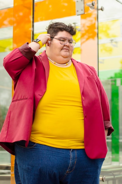 Retrato de una mujer gordita usando auriculares en la calle