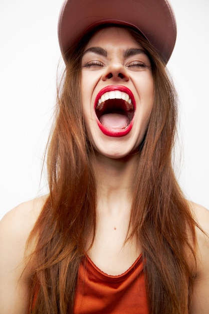 Retrato de una mujer con una gorra boca abierta lengua ojos cerrados labios rojos divertidos vista recortada