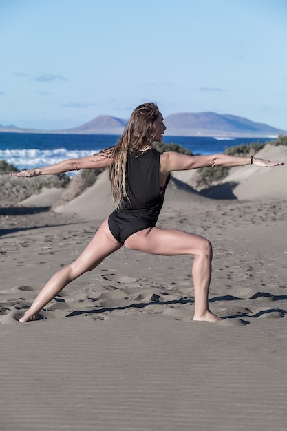 Retrato de una mujer haciendo yoga en la playa