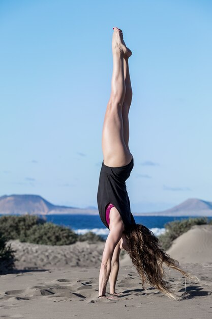 Retrato de una mujer haciendo yoga en la playa