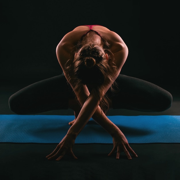 Foto retrato de mujer haciendo yoga sobre muro oscuro