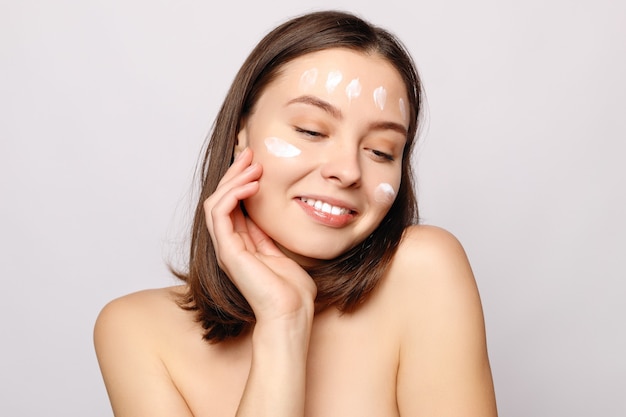Foto retrato de mujer hermosa aplicando crema facial
