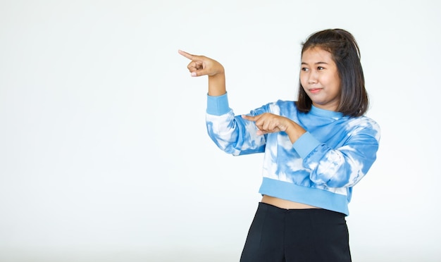 Retrato de mujer hermosa asiática con poses de camisa casual, señalando publicidad sobre fondo blanco, espacio de copia en blanco con una mirada aislada y sonriente a la cámara.