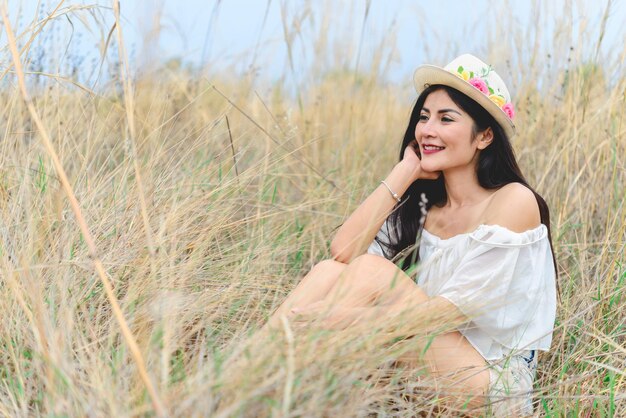 Retrato de mujer hermosa asiática que se siente fresca en el denim de campo con sombrero de paja