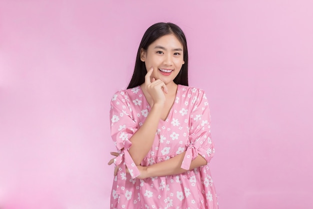 Retrato de mujer hermosa asiática en vestido rosa y cabello largo negro Sus manos tocan la sonrisa de la mejilla