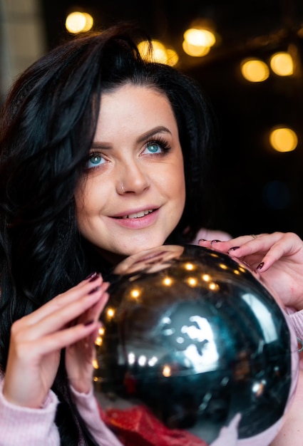 Retrato de mujer hermosa con bola decorativa. Señora bonita que muestra la bola de Navidad en las manos.