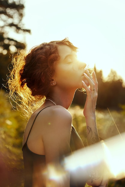 Retrato de mujer hermosa en el bosque al atardecer. La mujer está descansando en la naturaleza, un retrato de arte en los rayos del sol