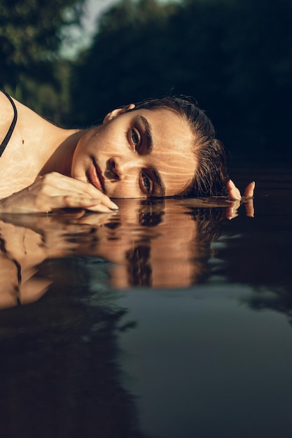 Retrato de una mujer hermosa con el cabello mojado en el agua del lago mirando a la cámara