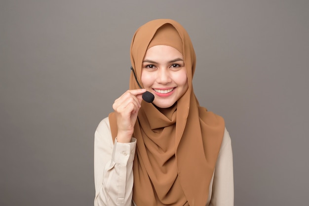 Retrato de mujer hermosa call center con hijab en gris