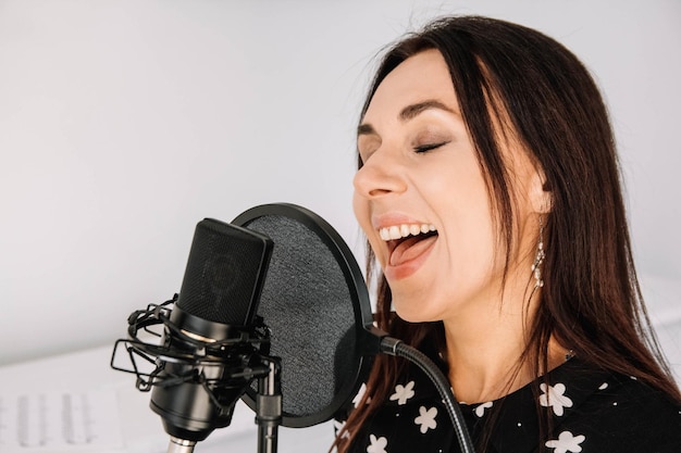 Retrato de mujer hermosa canta una canción cerca de un micrófono en un estudio de grabación