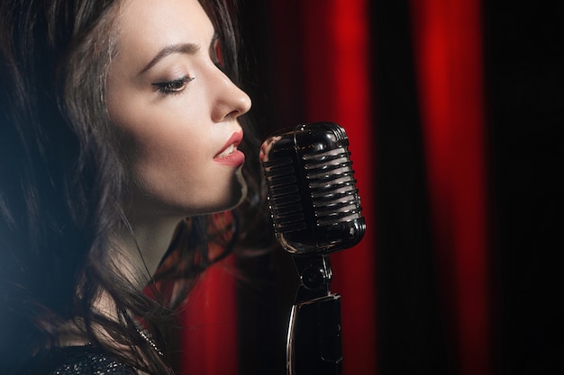 Foto retrato de mujer hermosa cantando en el micrófono