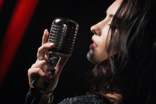 Retrato de mujer hermosa cantando en el micrófono