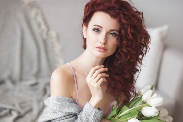 Retrato de mujer hermosa en casa con un ramo de flores