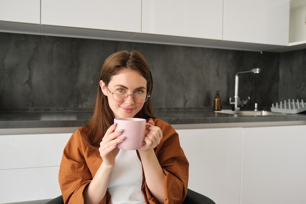 Foto retrato de una mujer hermosa en la cocina bebiendo café en casa pasando tiempo en el interior disfrutando de lo acogedor