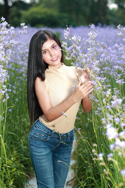 Retrato de mujer hermosa divirtiéndose y disfrutando entre flores Naga-crested field en la naturaleza