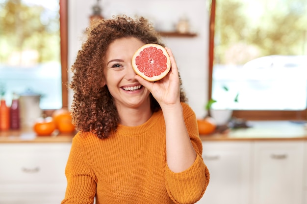 Foto retrato de mujer hermosa divirtiéndose con frutas en la cocina