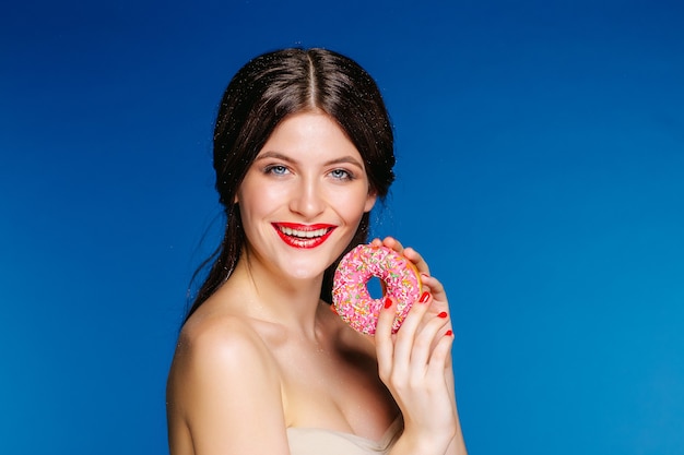 Retrato de mujer hermosa con donut aislado sobre fondo azul.