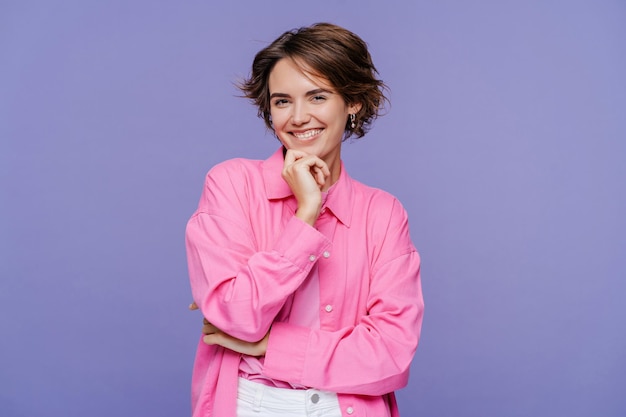 Retrato de una mujer hermosa con una elegante camisa rosa mirando a la cámara posando