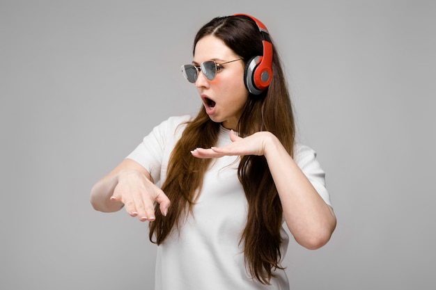 Retrato de mujer hermosa emocional en auriculares y gafas de sol escuchando música