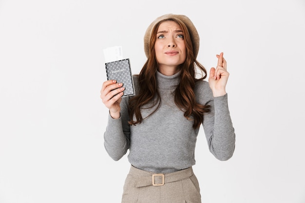 Retrato de mujer hermosa emocional con pasaporte con boletos aislados en la pared blanca.