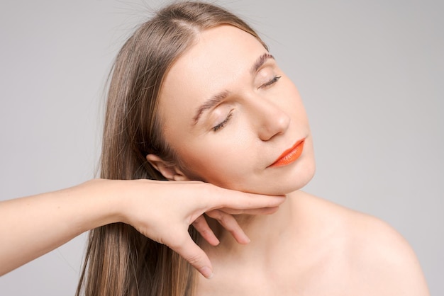 Retrato mujer hermosa feliz con lápiz labial naranja brillante mano femenina toca