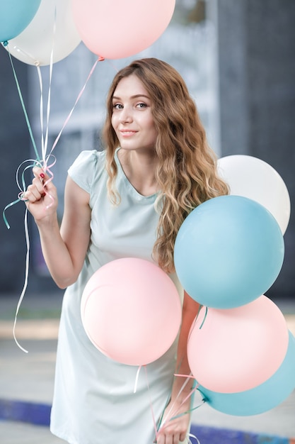 Retrato de mujer hermosa con globos multicolores voladores al aire libre