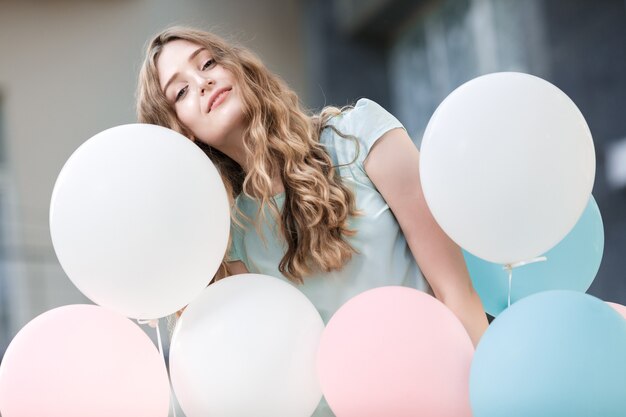 Retrato de mujer hermosa con globos multicolores voladores al aire libre