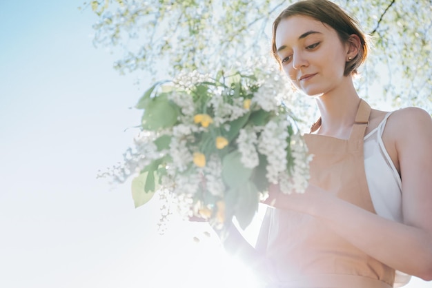 Retrato de mujer hermosa haciendo corona de flores dientes de león en campo de flores Estilo de vida de verano amante de la naturaleza y concepto de libertad Taller de floristería Fondo romántico de floristería en el trabajo