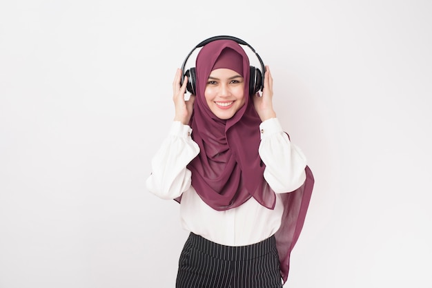 Retrato de mujer hermosa con hijab es disfrutar escuchando música sobre fondo blanco.