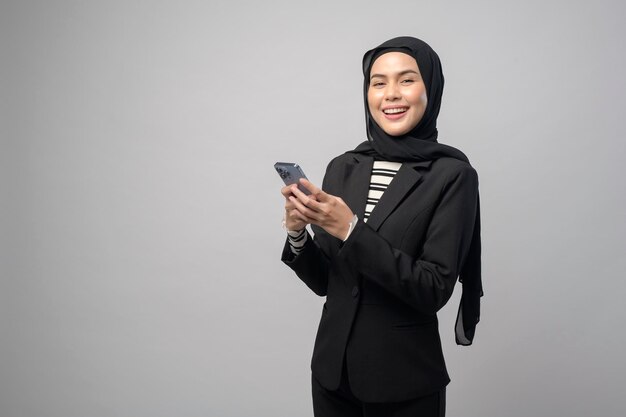 retrato, de, mujer hermosa, con, hijab, utilizar, teléfono celular, blanco, plano de fondo