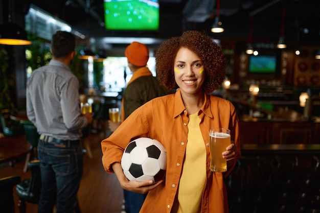 Retrato de mujer hermosa hincha de fútbol con vaso de cerveza