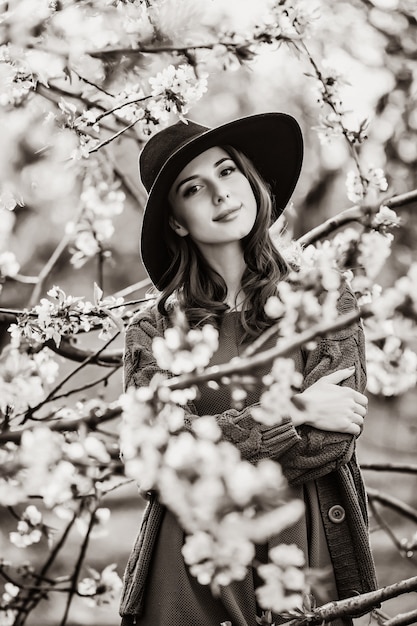 Retrato de una mujer hermosa en jardín de manzano en flor en primavera en el atardecer. Imagen en estilo de color blanco y negro