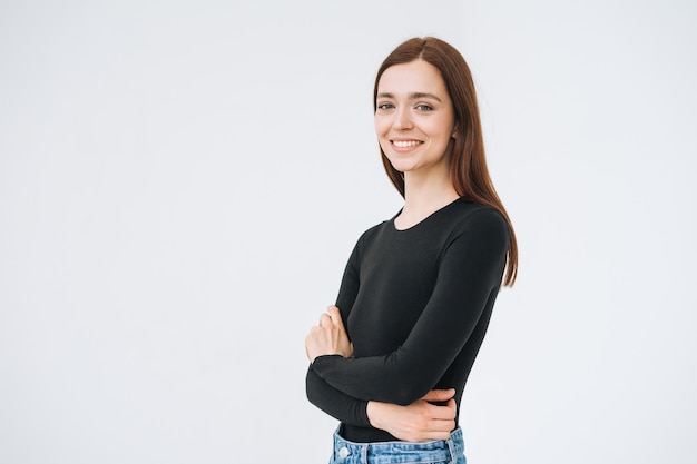 Retrato de mujer hermosa joven feliz con cabello largo oscuro en manga larga negra y jeans sobre fondo blanco aislado