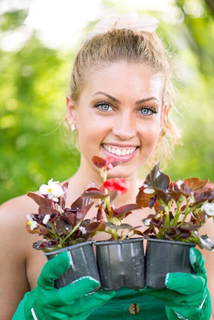 Retrato de mujer hermosa joven sosteniendo una olla con flores.