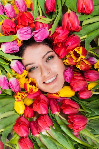 Retrato de una mujer hermosa joven con tulipanes alrededor de su rostro La niña yace en las flores dadas para el 8 de marzo Día Internacional de la Mujer