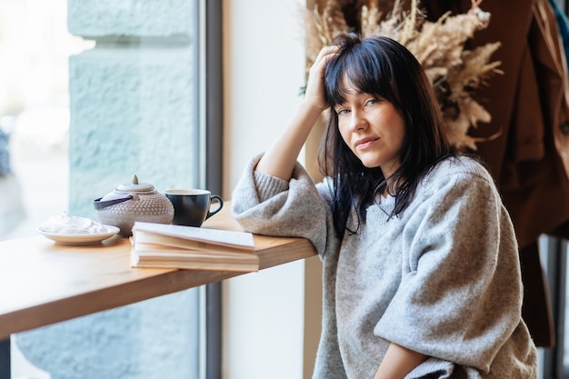 Retrato de mujer hermosa leyendo un libro mientras se relaja en la cafetería. niña en el café, libro, lectura, café