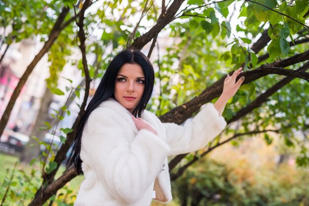 Retrato de mujer hermosa morena en chaqueta de piel en el parque otoño