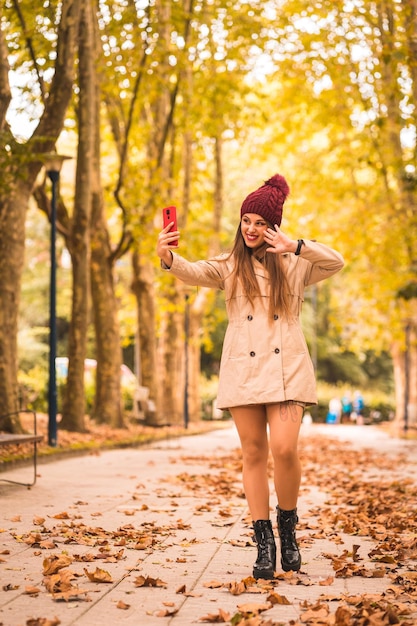 Retrato de una mujer hermosa en otoño junto a un bosque en la naturaleza haciendo una videollamada