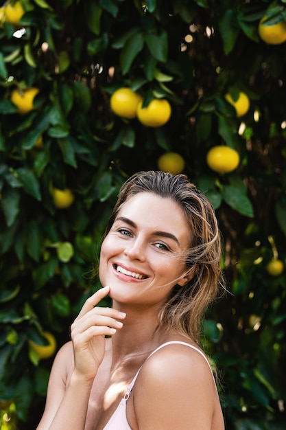 Retrato de mujer hermosa con piel suave contra limoneros