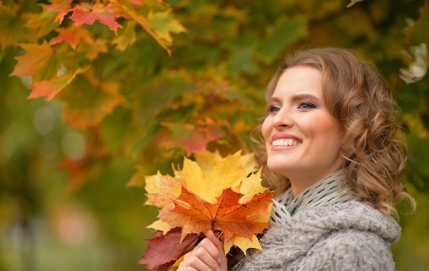 Retrato de mujer hermosa posando al aire libre en otoño con hojas