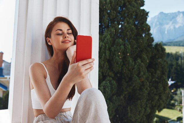 Retrato de una mujer hermosa que usa el teléfono mira la pantalla en un hotel cómodo una vista abierta de lo inalterado